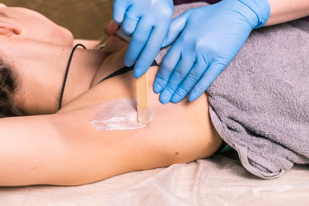 Waxing woman armpit. Salon wax beautician epilation procedure. Waxing female body for hair removal
