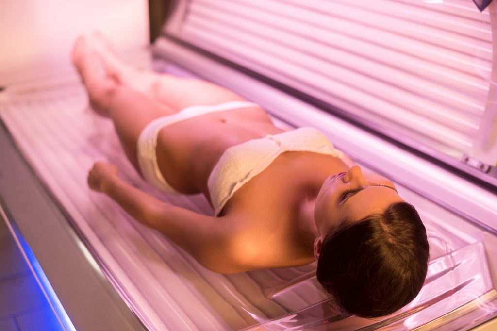 Woman on tanning bed. Top view of attractive young woman lying on tanning bed